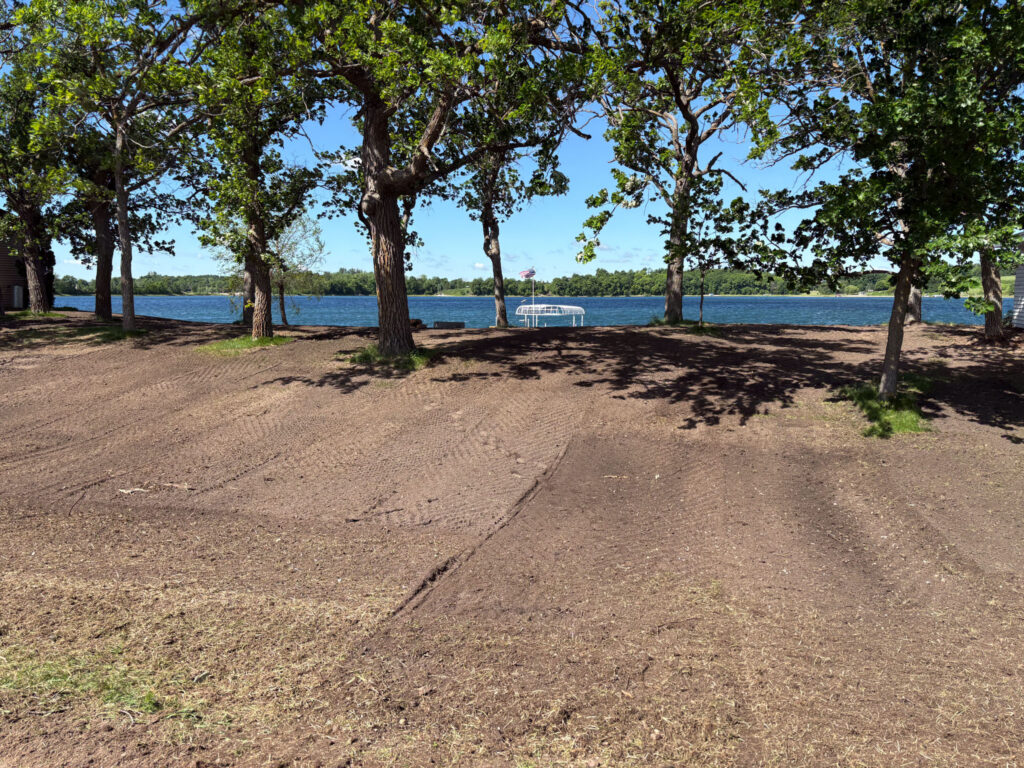 Lake property that has been leveled and has a few trees in the background.