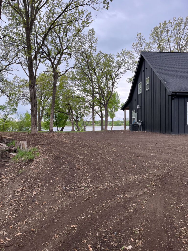 Trees and a house with leveled dirt around it.